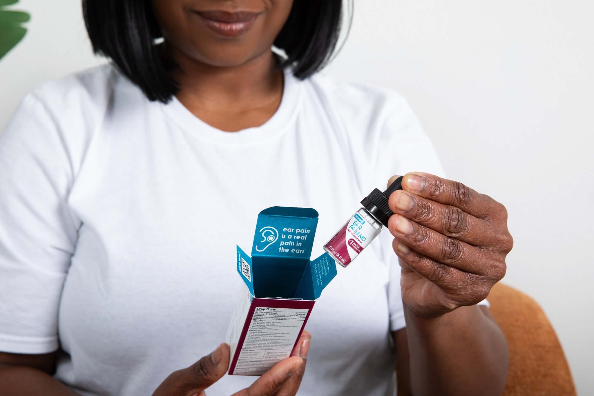 Woman holding an open medicine box and bottle, looking ready to alleviate pain.